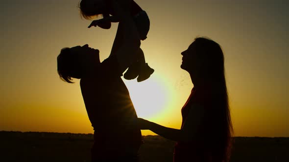 Cheerful Family with Baby Girl Relaxing at Sunset