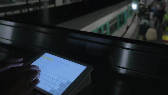 Woman Typing Message on Pad in Subway