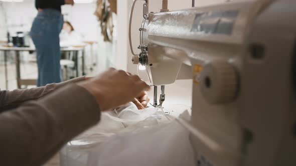 Hands of Seamstress Who Stitching Tulle on Sewing Machine and Cutting Off Thread with Scissors