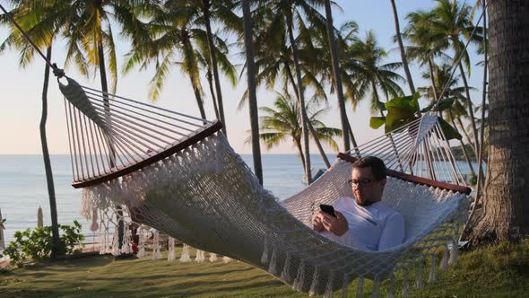 Man Enjoying Vacation on Sea Shore and Swinging in Hammock