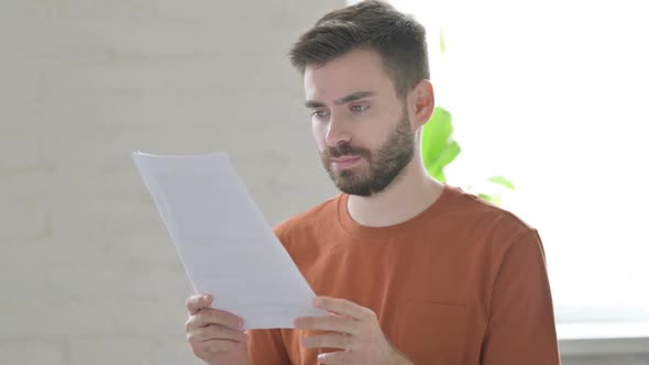 Young Man Reading Documents for Work Paperwork