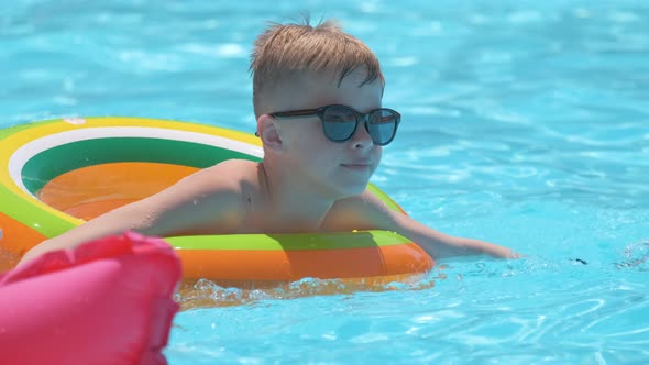 Portrait of Happy Child Boy Relaxing in Inflatable Circle in Swimming Pool on Sunny Summer Day