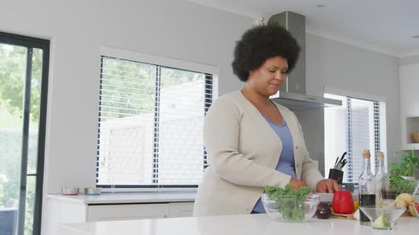 Video of plus size african american woman using tablet, preparing meal