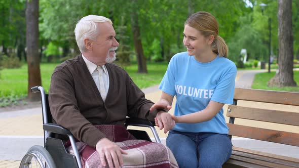 Kind Young Woman Volunteer T-Shirt Holding Disabled Male Hand