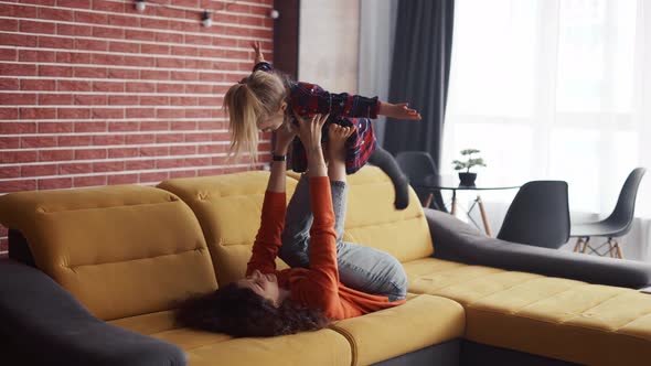Mother Lifting Girl in Air on Her Ankles Pretending to Fly at Home