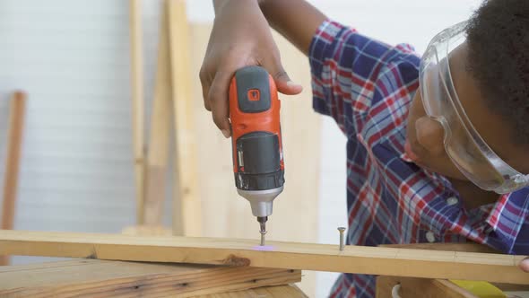 little child with a drill in hands and help dad assembling furniture shelf with power screwdriver 