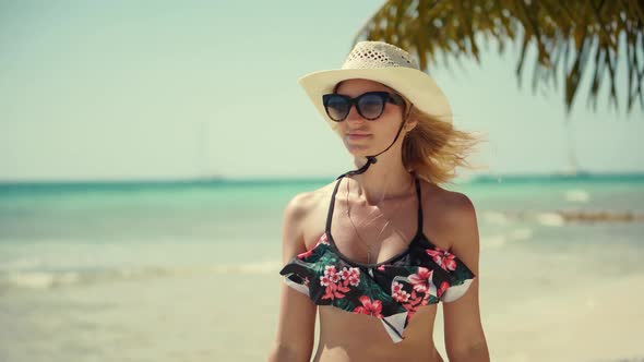 Girl In Bikini Walking On Tropical Hawaii Beach.Tanned Woman In Swimsuit And Hat Walks Along Beach