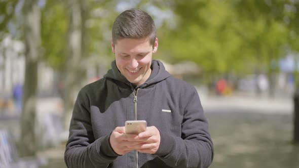 Smiling Young Man Using Mobile Phone Outdoor