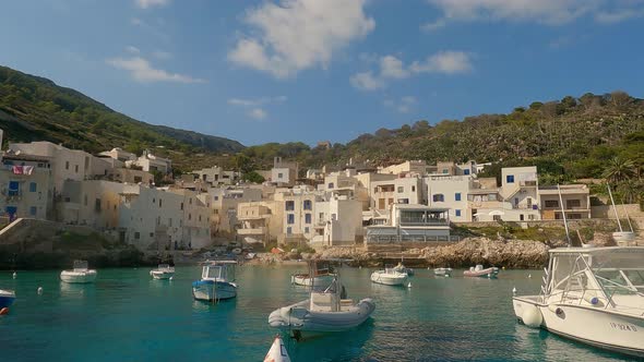 View of Levanzo Sicilian fishing village and waterfront scenic bay with moored boats in foreground,