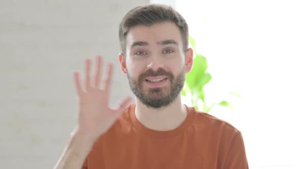 Young Man Waving Hand to Say Hello
