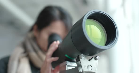 Young Woman observe through telescope