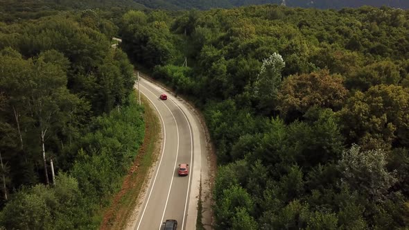 Orange SUV Car Driving on a Rural Road in the Mountains and Forest at Summer Sunny Day - Drone Point