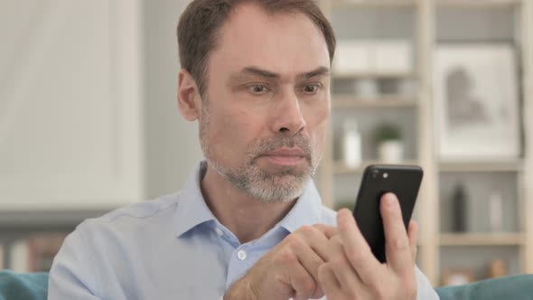 Senior Aged Businessman Celebrating Success on Smartphone