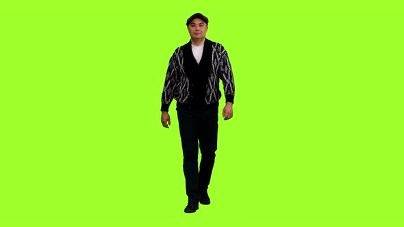 A Man in Cardigan and Flat Cap Walks on Green Background