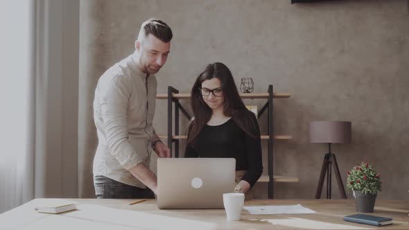 Male Coworker Showing Document with Project Results Talking to Caucasian Female Colleague