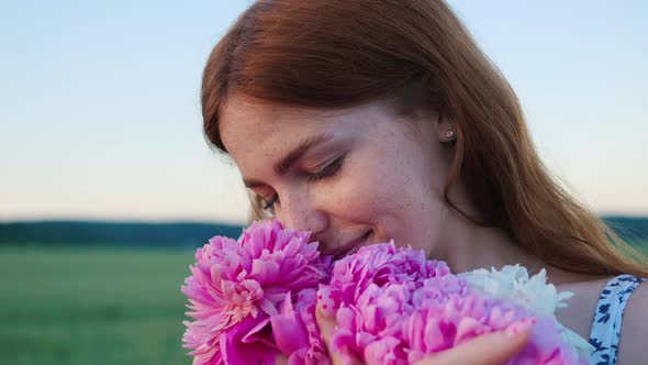 Woman Holding Pink Flowers Enjoying Fresh Air on the Nature at Sunset