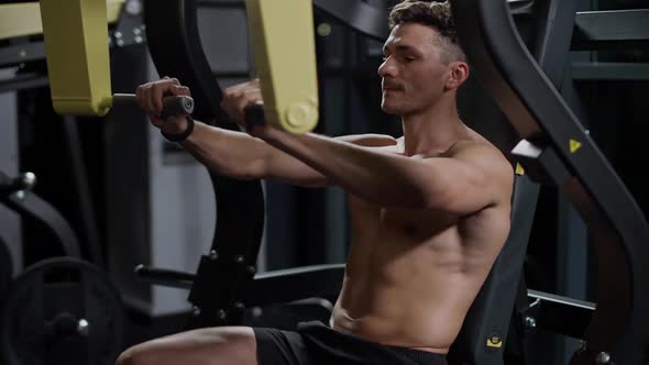 Athletic Man in the Gym Lifting Blocks on Gym Machine Training on Block Device Night Training