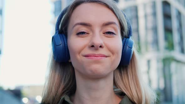 Happy Young Woman in Headphones Listening to Music in Urban Town