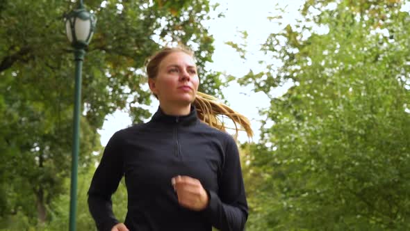 Fit woman jogging under trees in park