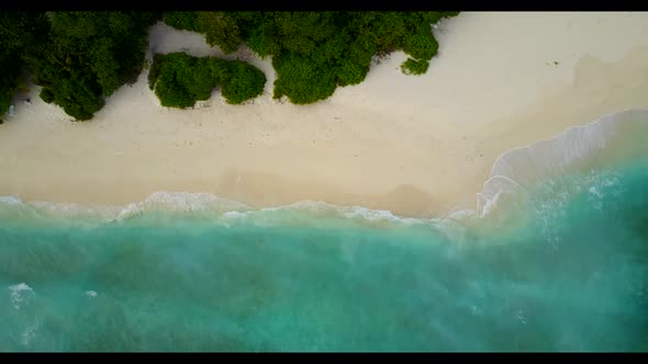 Aerial flying over panorama of tropical shore beach adventure by aqua blue ocean with clean sandy ba