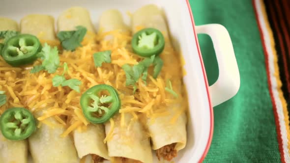 Chicken enchiladas with cheddar cheese and sauce.