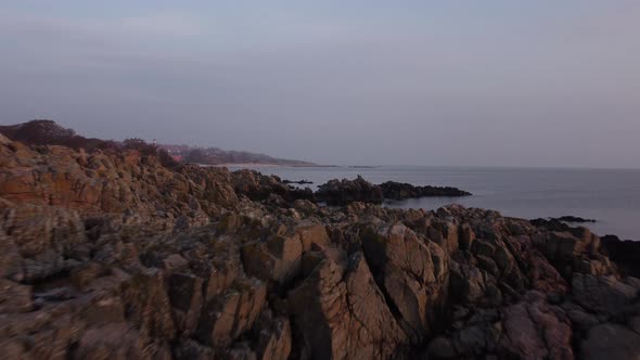 Flyover Shot of Scattered Rock Formation in the Majestic Shore of a Calm Ocean