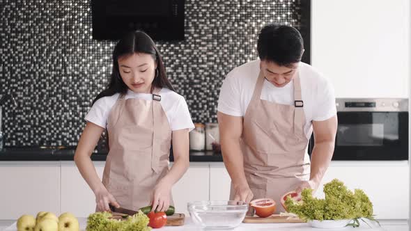 Portrait of Happy Young Asian Couple Cooking Together in the Kitchen at Home