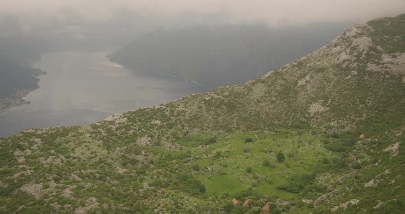 Helicopter aerial behind small jet flying near coastline, then moving above jet, foggy day