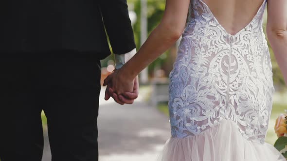 Woman in Lacy Dress and Man in Suit Walk Along Summer Park