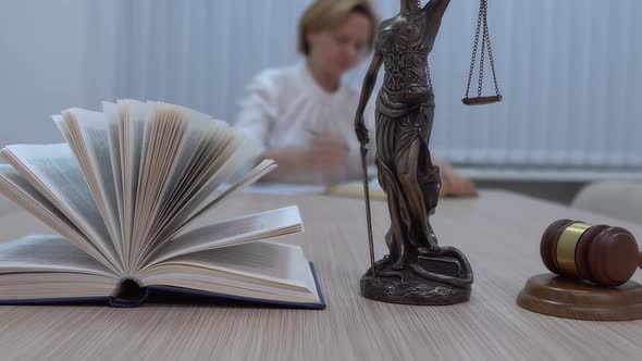 a Lawyer in the Workplace Examines Documents and Legislation the Statuette of Themis with a Master