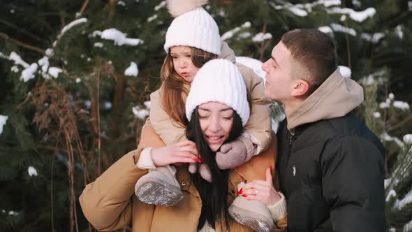 Parents with Daughter Walking in Forest in Winter