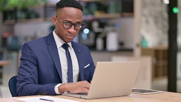 African Businessman with Laptop Doing Thumbs Up in Office 