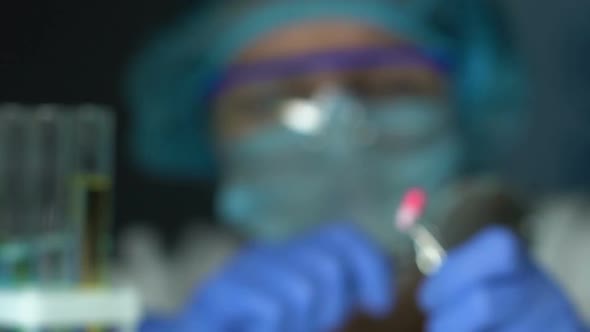 Female Researcher Looking at Pill in Forceps Through Magnifying Glass Drug Test