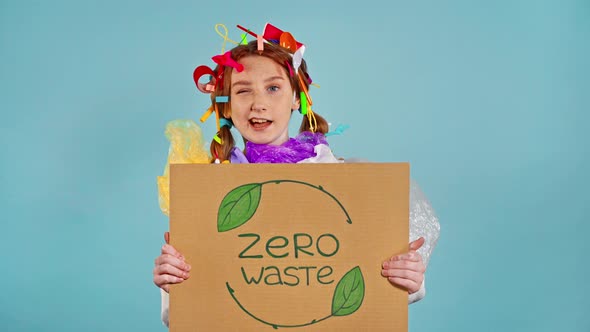 Girl with plastic trash on herself holding placard with inscription zero waste