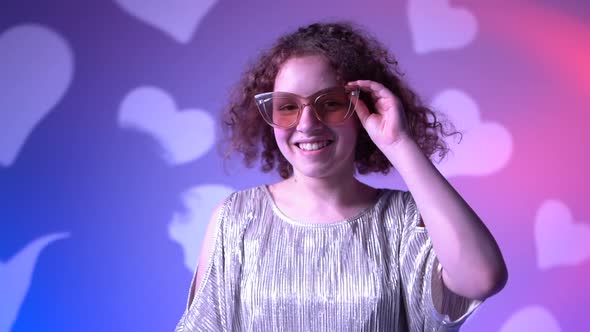 Close Up Portrait of a Young Curly Haired Girl in a Shiny Dress and Fashionable Glasses