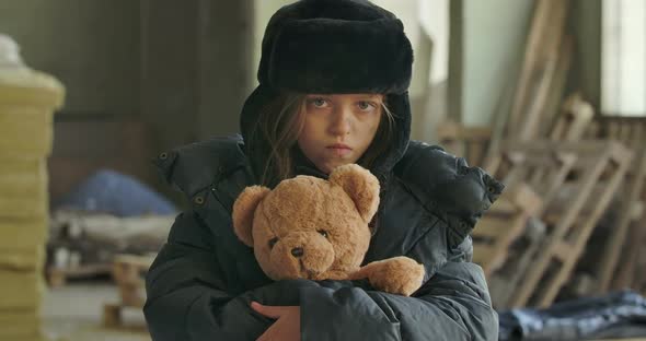 Portrait of a Homeless Girl with Grey Eyes Wearing Hat with Earflaps Looking at the Camera