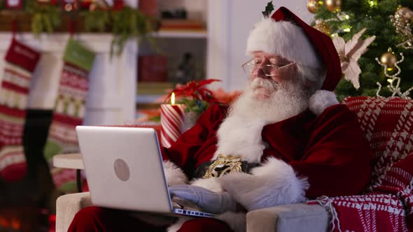 Santa Claus using laptop in living room