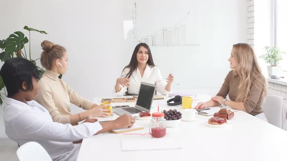 Young Modern Caucasian and African Businesswomen Presenting Meeting in Light Office