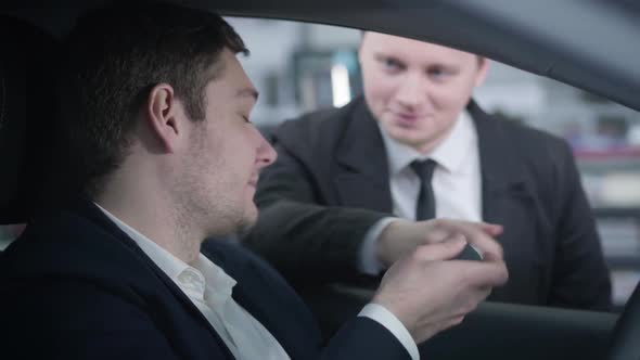 Close-up Side View of Confident Caucasian Man Taking Car Keys From Dealer and Starting Engine