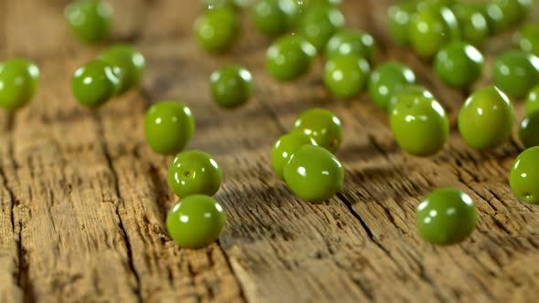 Super Slow Motion Shot of Rolling Fresh Green Olives on Old Wooden Table at 1000 Fps.