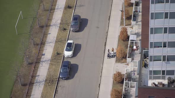 Two females couple walking with strollers in city top down aerial view from balcony - People walking