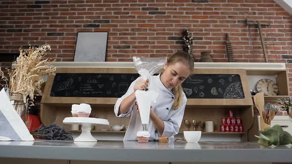 Young Confectioner Putting Cream on the Cake Using Pastry Bag