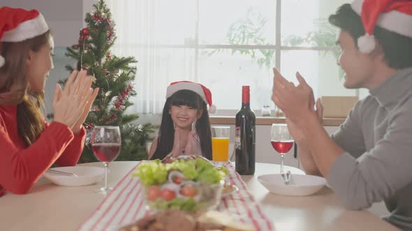 Asian young girl excited for dinner and food to celebrate Xmas holiday on table with parents at home