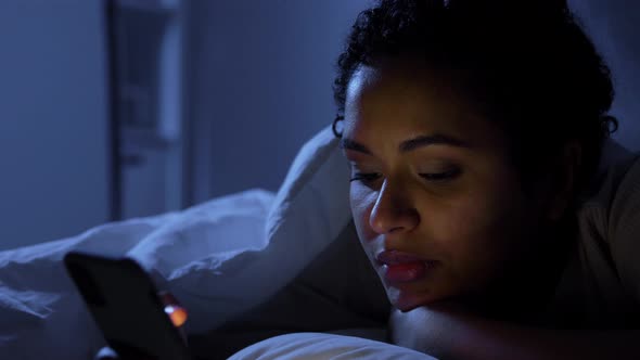 Woman with Smartphone in Bed at Home at Night