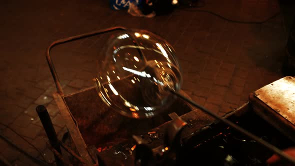 Glassblower heating a piece of glass in furnace