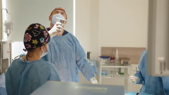 Professional Surgeons Turning on Surgery Lights While Bending Over Patient