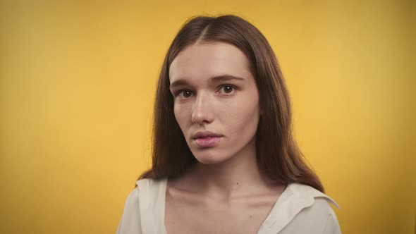 Portrait of a Young Adult Caucasian Woman is Looking at Camera on a Bright Yellow Background