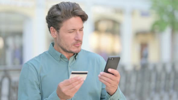 Outdoor Middle Aged Man having Online Payment Failure on Smartphone