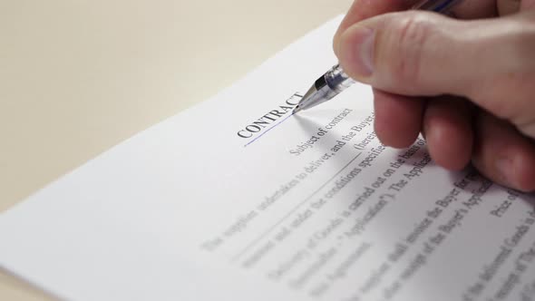 The Hand of the Business Person Emphasizes the Word "Contract" on the Document