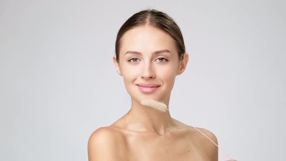 Beautiful Young Woman with Clean Fresh Skin Standing Over Light Grey Background